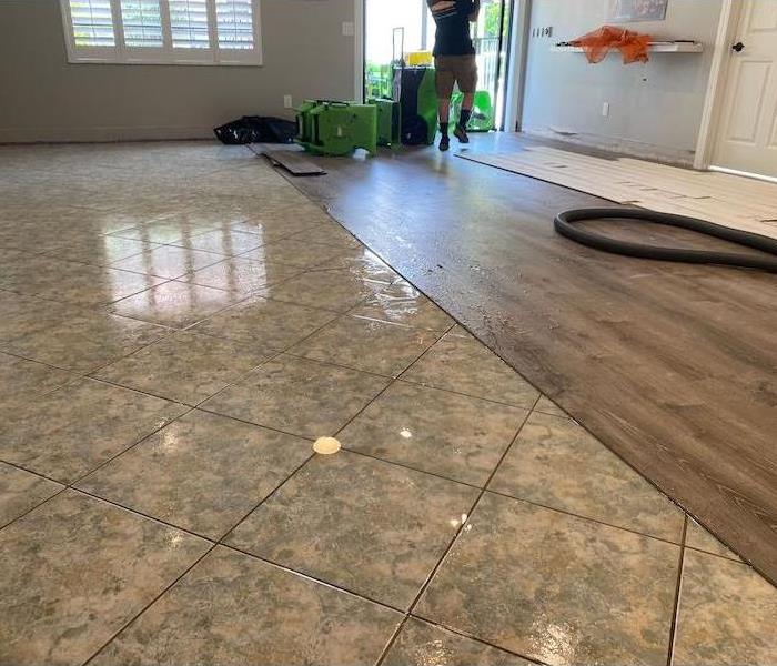 Floating floor with tile and partially removed wood floorboards with SERVPRO drying equipment
